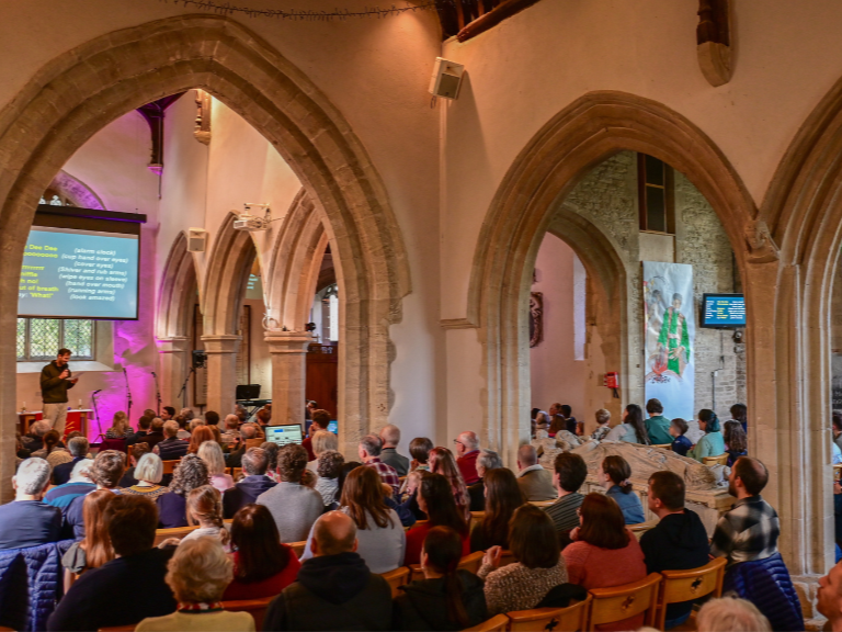 The congregation gathered beneath the stone arches of St Mary's Cogges