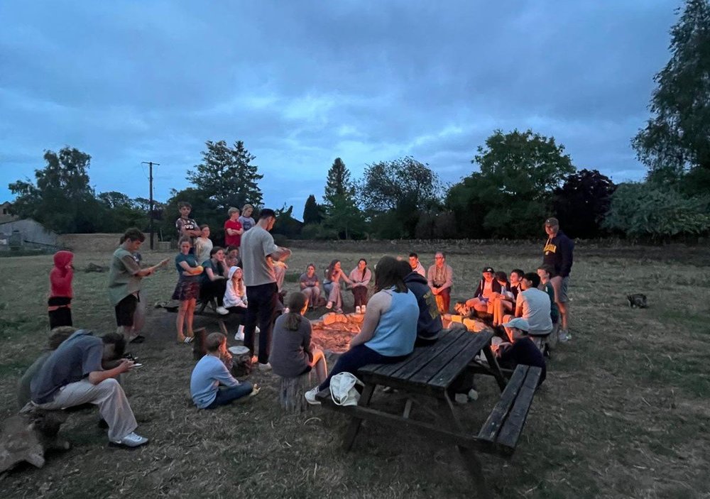 Cogges young people gathered around a campfire outdoors